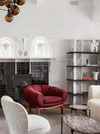 Комната с камином и мягкой мебелью: ансамбль кресел и диванов разных форм и цветов на фоне белых стен и больших арочных окон в викторианском интерьере, добавляющий контраст и глубину.