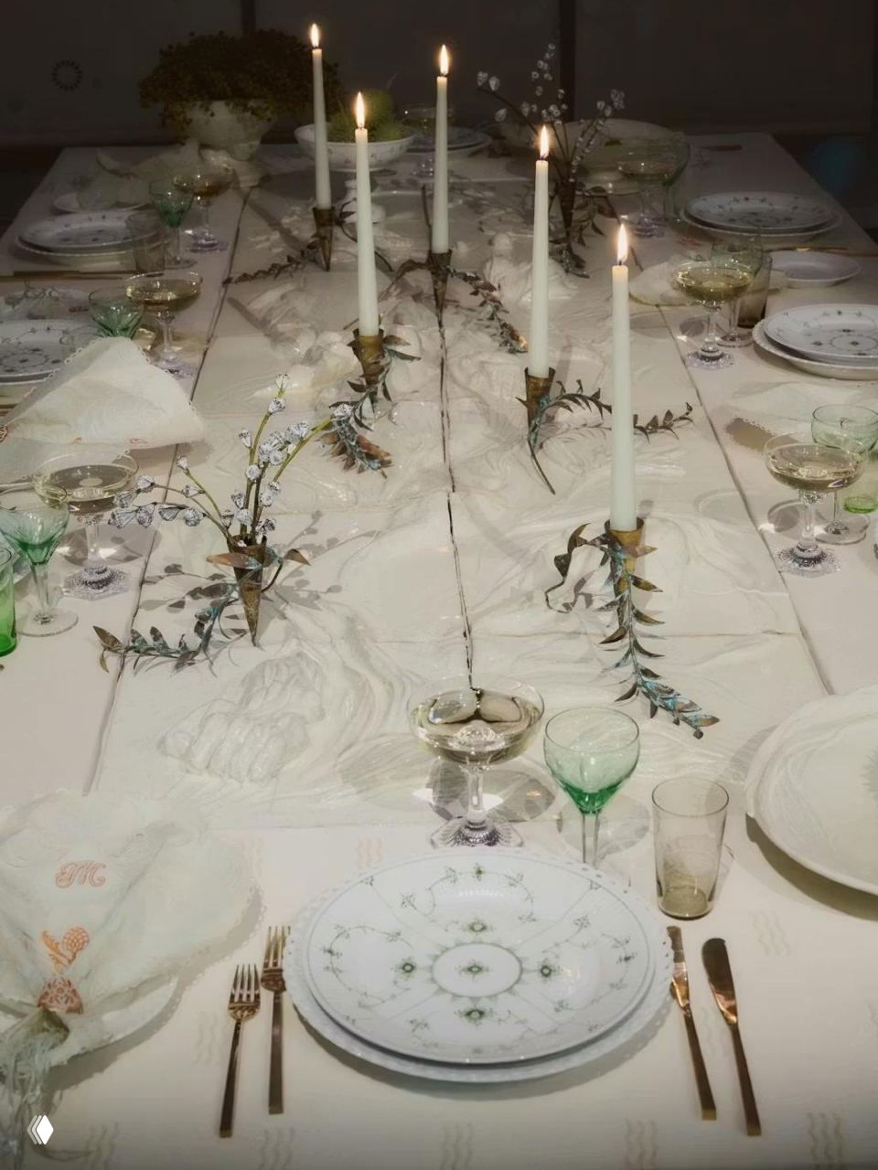 Длинный белоснежный стол с высокими тонкими свечами, хрупкой фарфоровой посудой и изящной праздничной расстановкой элементов для особого ужина.