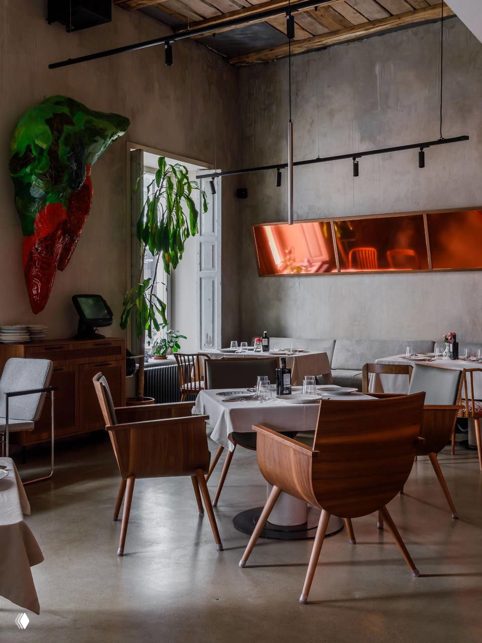 Общий план зала с деревянными креслами, столами под белыми скатертями, медный рефлектор и зелёные растения у окна в интерьере