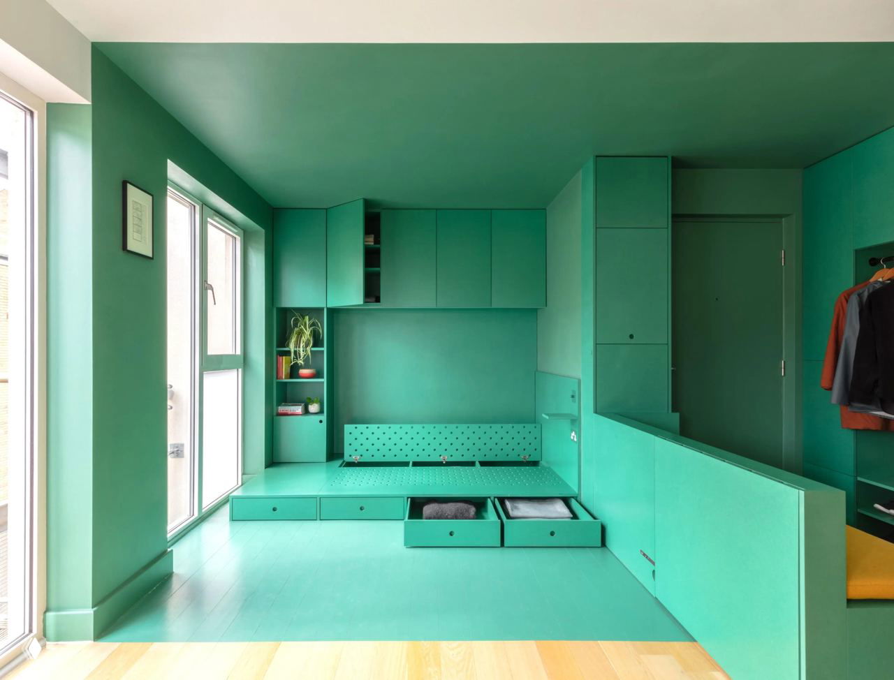 Вид с открытыми выдвижными ящиками в подиуме и складной секцией, демонстрирующий места для хранения и гибкость планировки в 9 м²