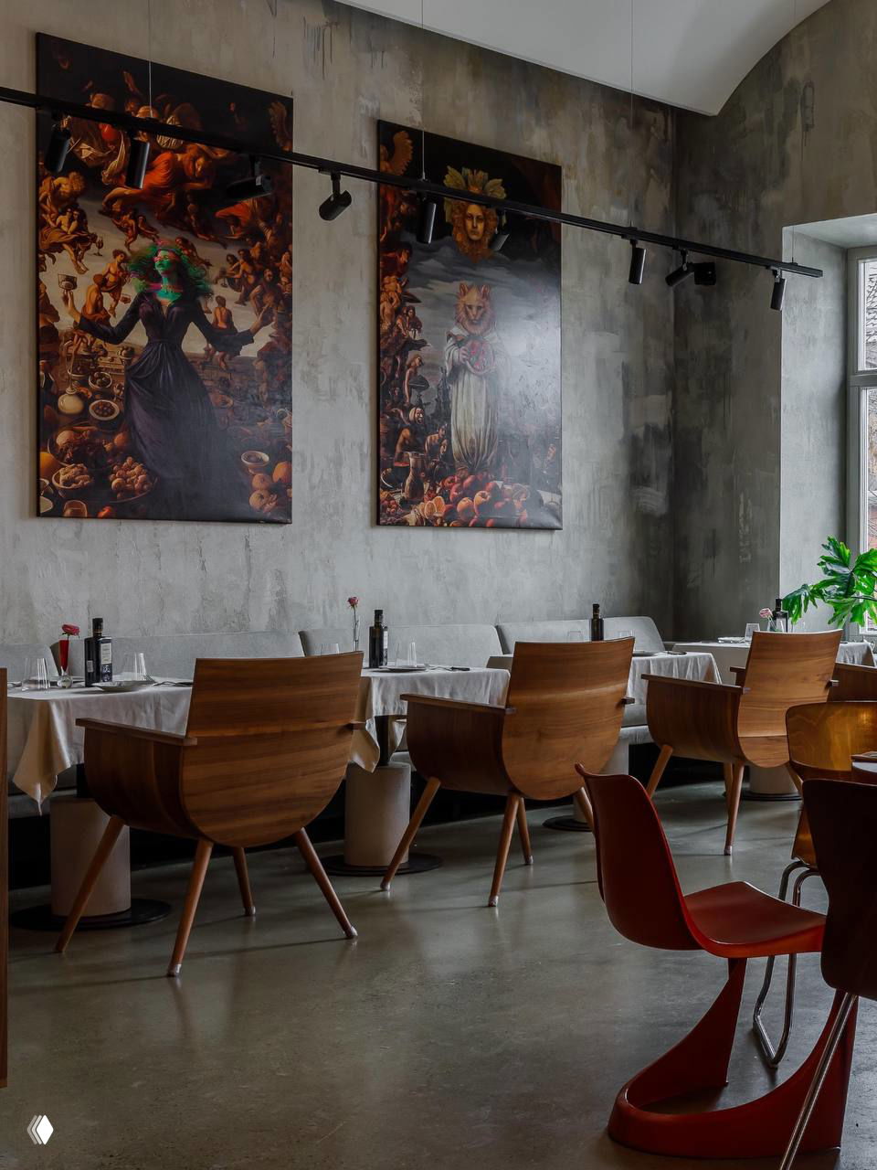 Стены из декоративного бетона, большие картины и ряды деревянных кресел с аккуратно сервированными столами в ресторане Madonna