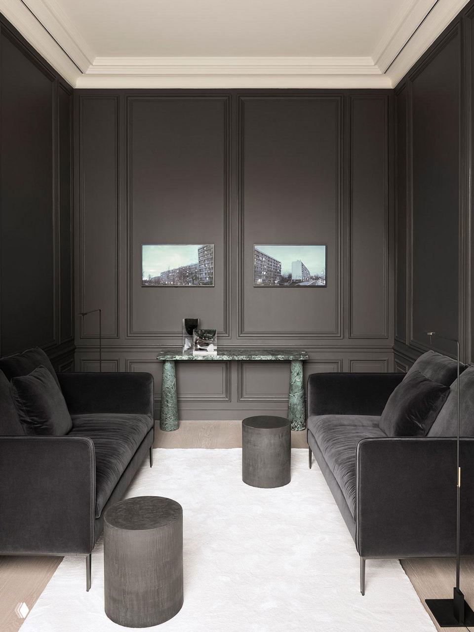 Небольшая кабинетная зона с глубокими тёмно-серыми стенами, двумя бархатными диванами и мраморной консолью — насыщенный монохромный интерьер.