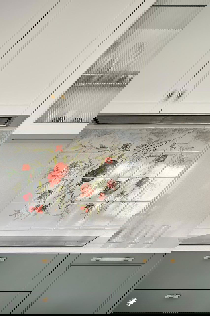 Фрагмент кухонного фартука с расписной керамической плиткой с изображением граната и зелёные нижние шкафы со столешницей.