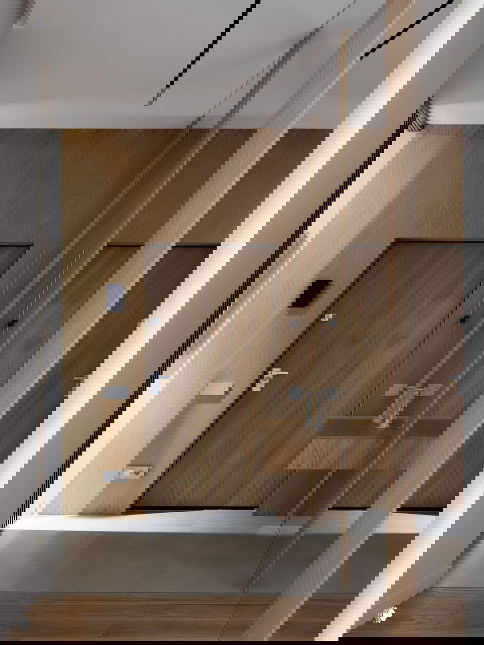 Коридор с круглым текстурным панно на светлой стене и деревянным полом, выдержанная нейтральная цветовая палитра интерьера.