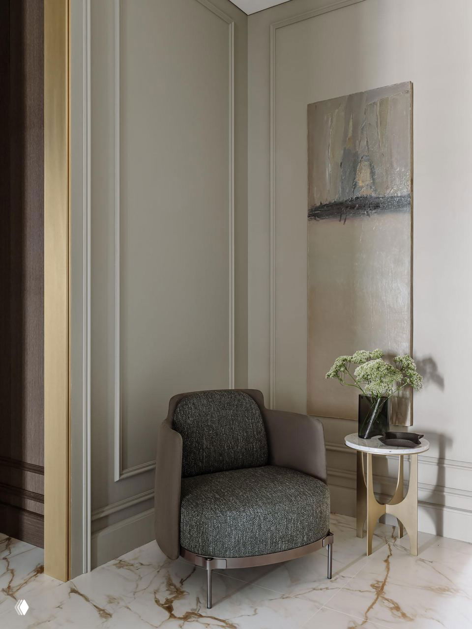 Небольшой уютный угол с дизайнерским креслом и мраморным столиком на фоне декоративных молдингов, благородного сочетания материалов и скрытой подсветки.