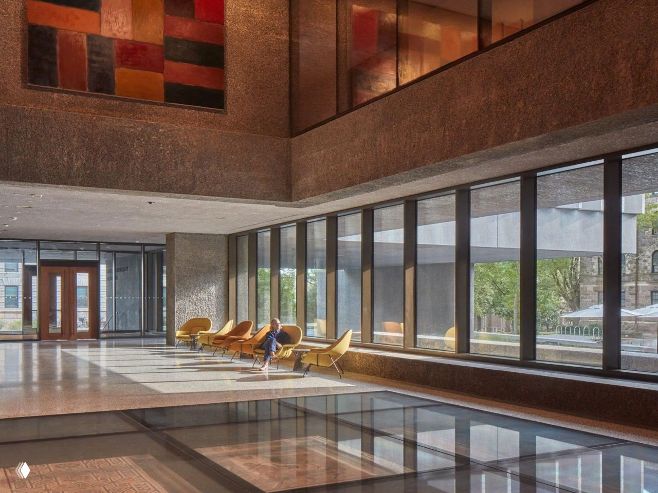 Внутреннее пространство музея: атриум с панорамными окнами, кресла у остекления и отражения на стеклянном полу.
