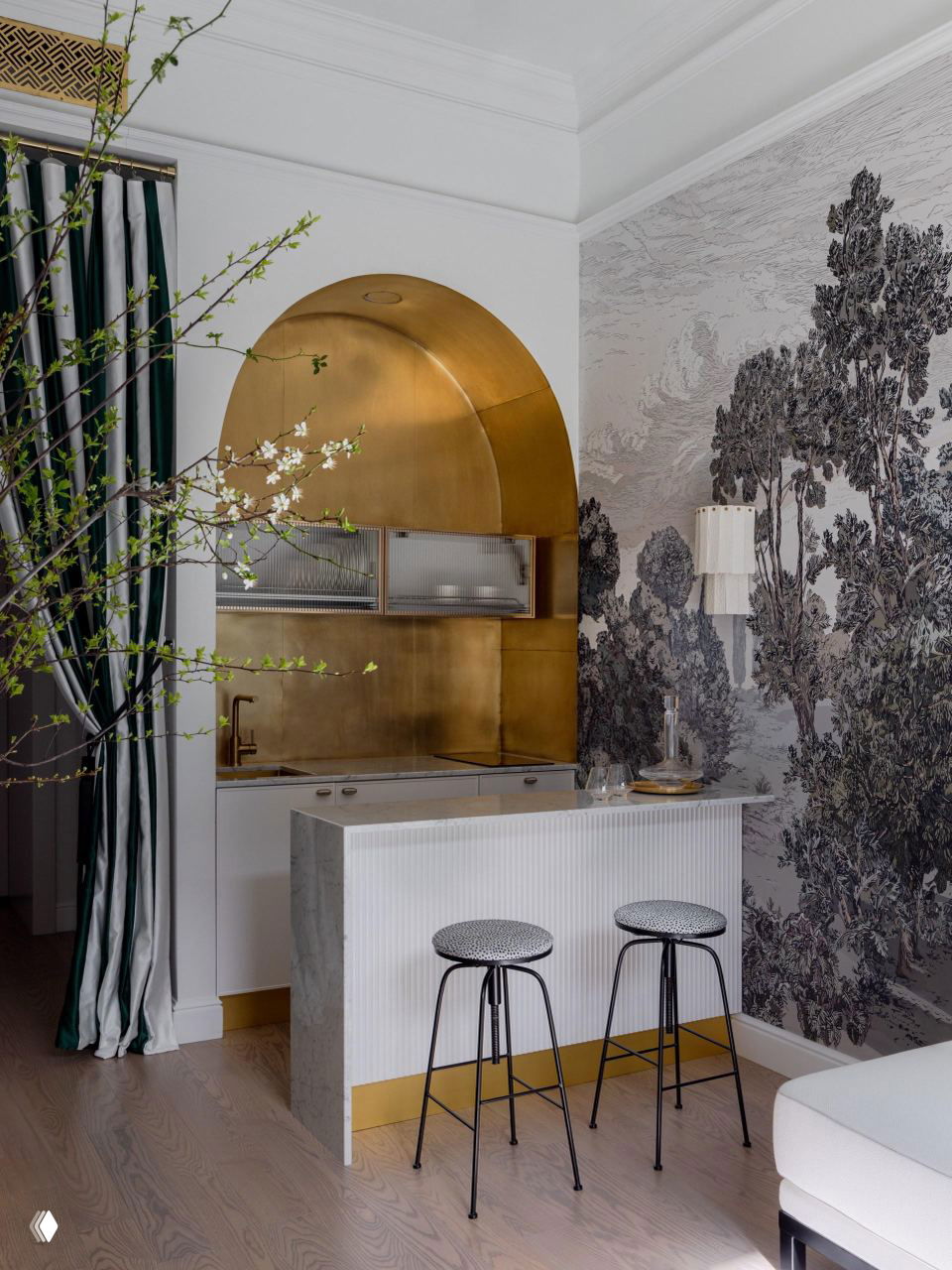 Компактная кухня с декоративной аркой и золотистой отделкой, небольшая барная стойка из мрамора и пару высоких табуретов для многофункционального пространства.