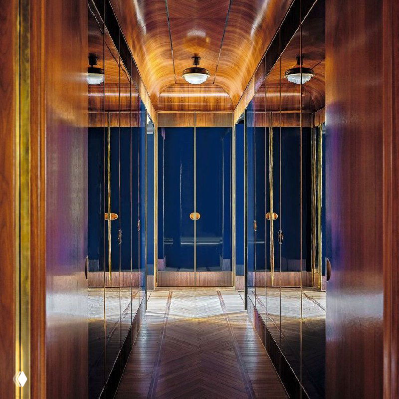 Интерьер комнаты с деревянной отделкой и встроенной мягкой скамьёй: насыщенные тёплые тона, текстурный ковер и элегантная подсветка.