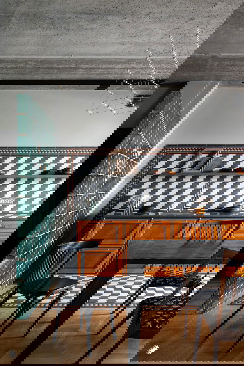 Кухня-гостиная с настенной и напольной шахматной плиткой, деревянными фасадами мебели, бетонным потолком и видом части интерьера квартиры в Казани.