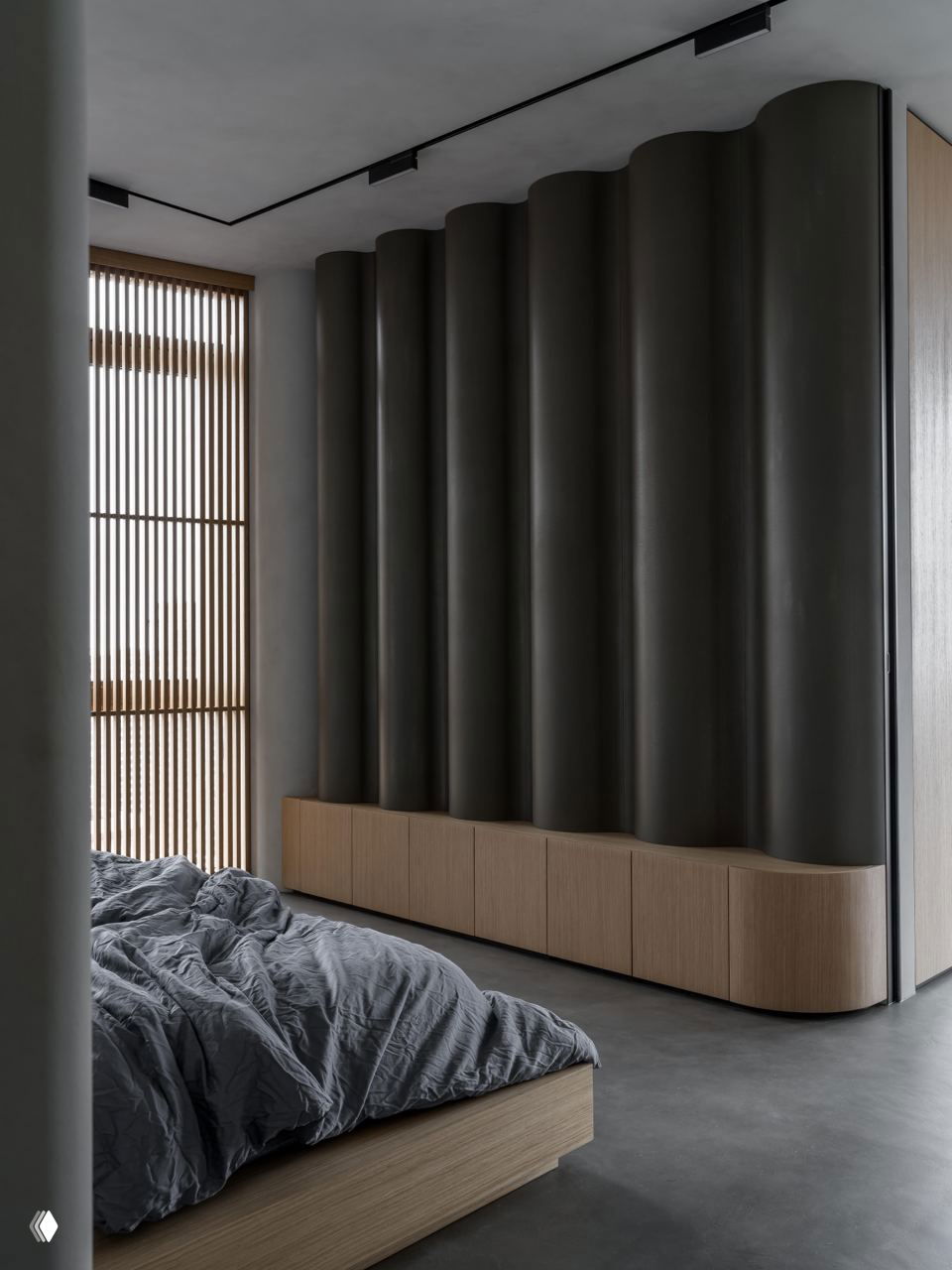 Спальня с большой волнообразной панелью-гардеробом, низкой деревянной тумбой и мягким текстилем — спокойная стерильная палитра и округлые формы.