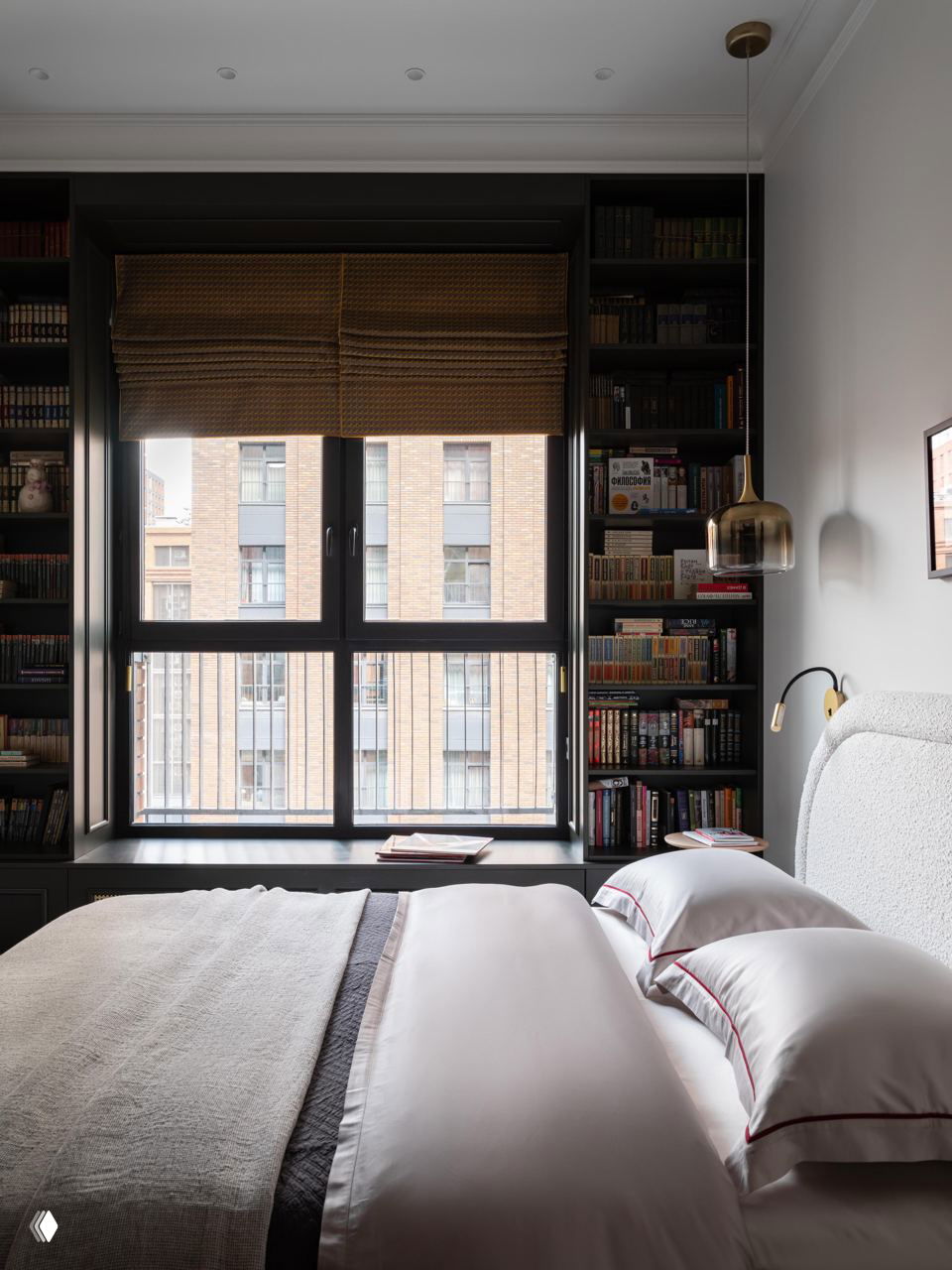 Спальня с большим окном и книжными полками по бокам: кровать, аккуратный текстиль и устроенные стеллажи с книгами и декором на фоне городского вида.