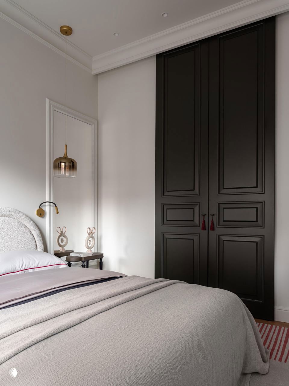 Ещё ракурс спальни: изящная кровать, встроенный высокий шкаф с чёрными дверцами и мягкая текстура покрывала в нейтральных тонах.