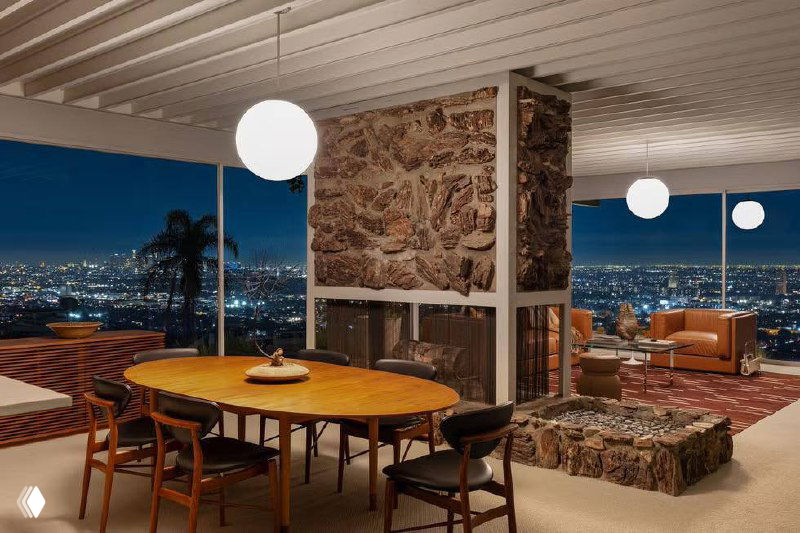 Ночной вид интерьера и подсветки дома Шталя: уютная зона отдыха на фоне огней Лос‑Анджелеса, отражения в стекле и драматичная городская панорама за пределами террасы.