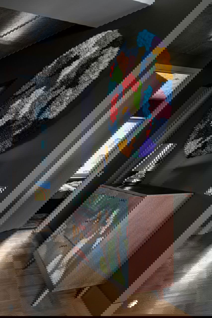 Прихожая или коридор с темными стенами, комод с художественной росписью и крупным круглым текстильным панно ярких цветов на стене.