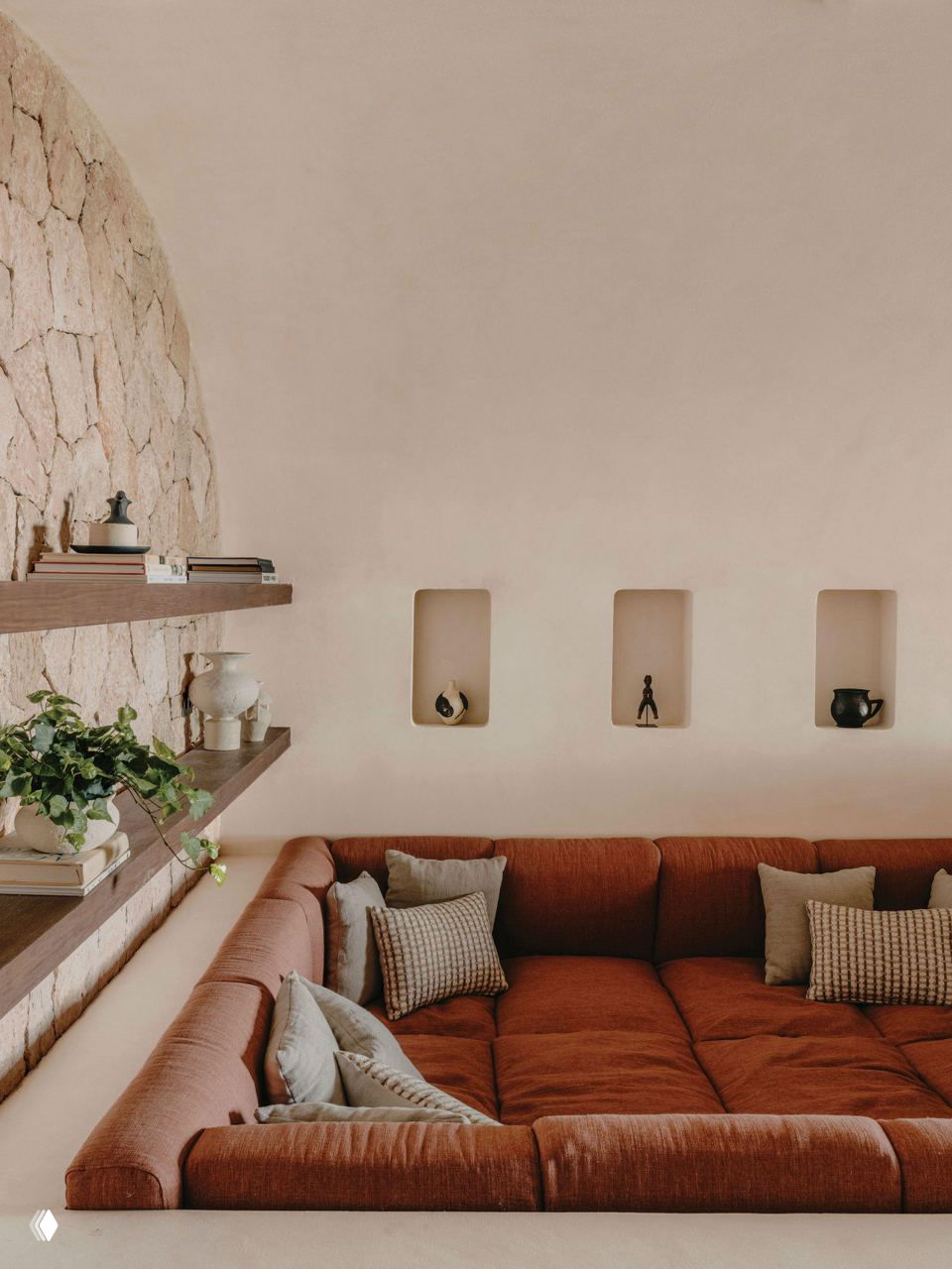 Встроенная мягкая зона с коричневым секционным диваном у стены с нишами и полками — уютная уголковая посадочная группа в минималистском интерьере.