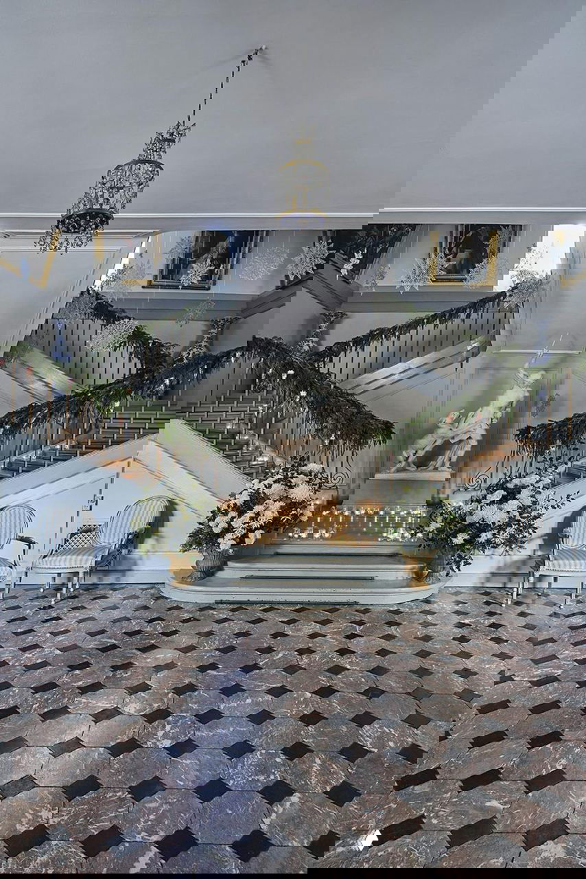 Интерьер главного холла датского поместья на острове Фюн: парадная лестница, гирлянды из хвои, мраморная статуя и множество зажжённых свечей на Рождество в поместье на Фюне.