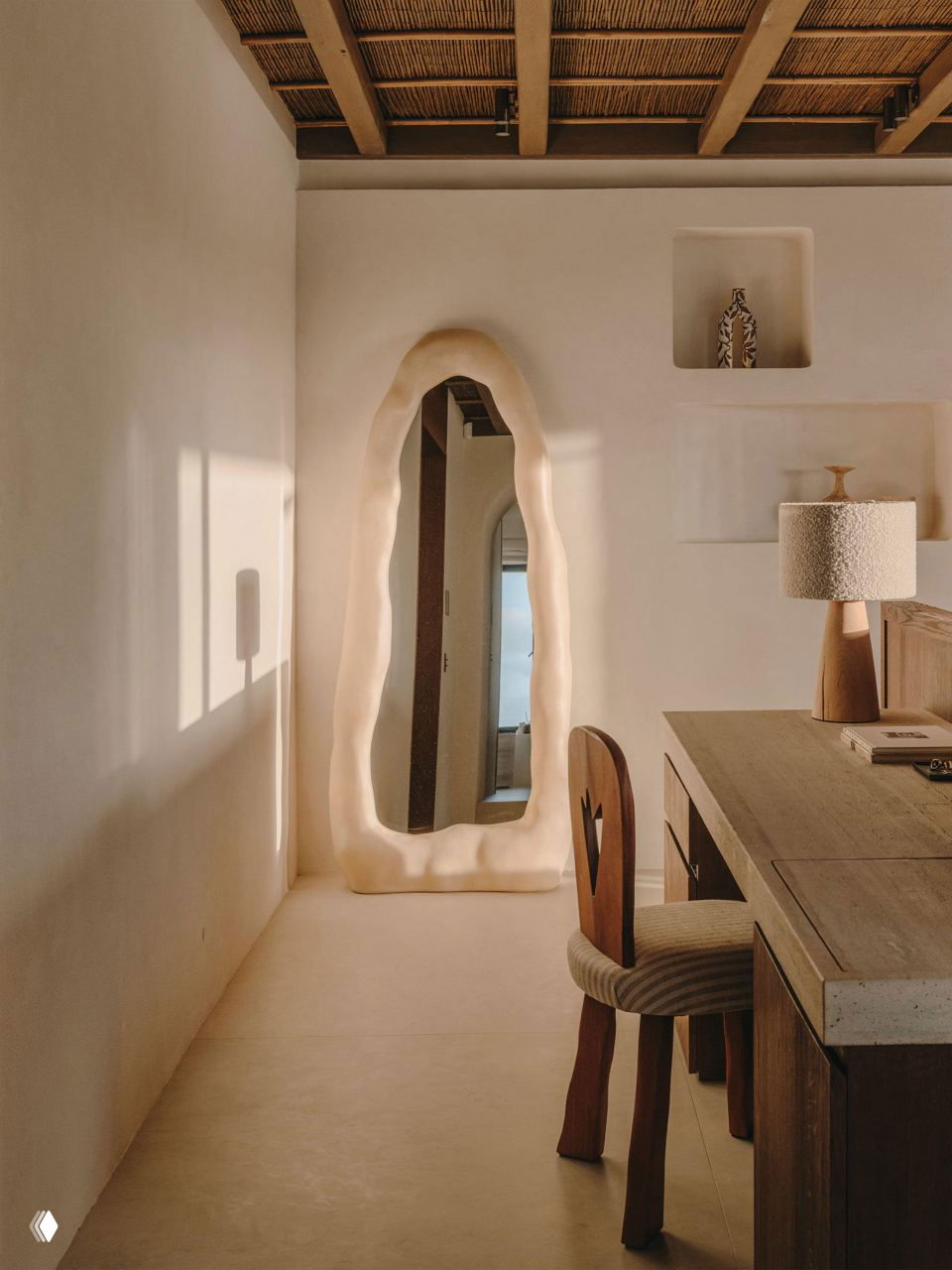Узкий коридор с дизайнерским зеркалом в рельефной рамке, мягким светом и деревянными элементами — деталь интерьера в теплой нейтральной гамме.