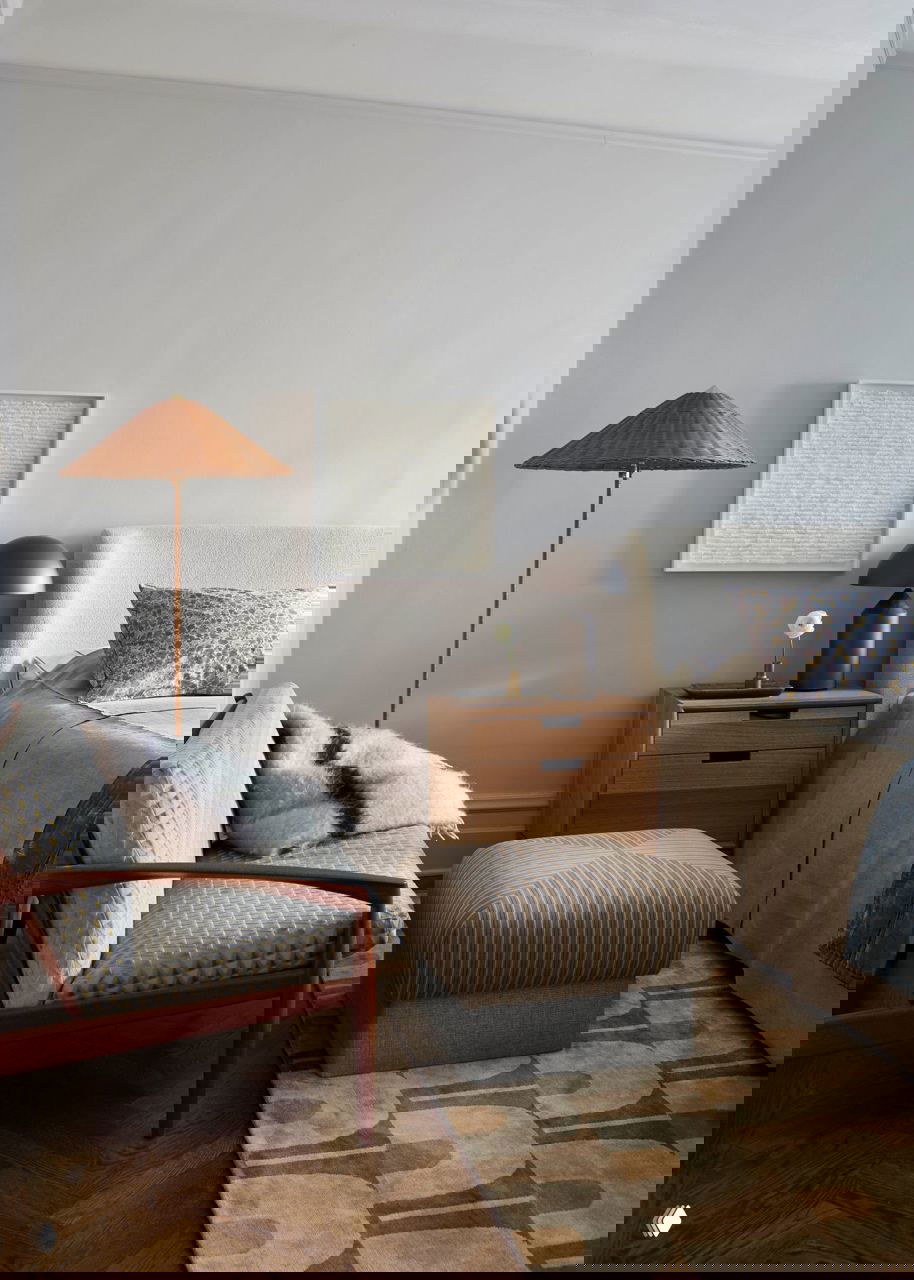 Спальня с мягким изголовьем, тёмной прикроватной тумбой и сдержанной текстильной палитрой — спокойная зона отдыха внутри квартиры.