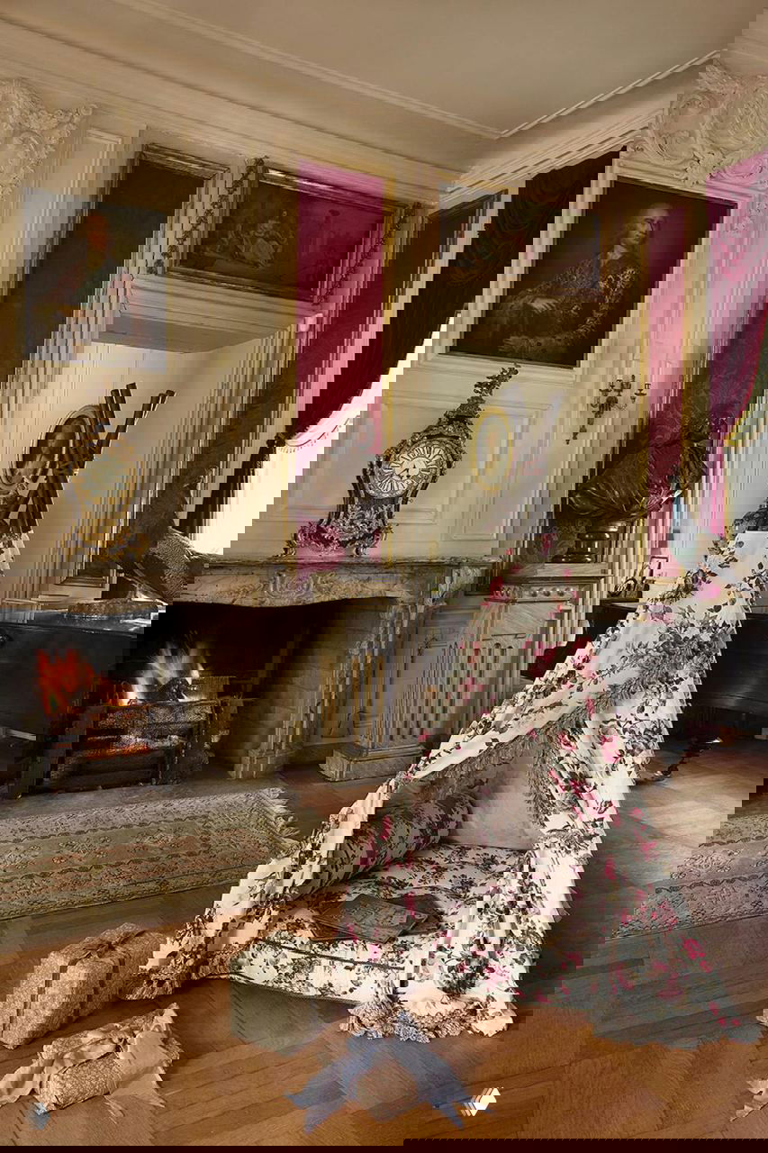 Уютный уголок с камином в поместье: тканевый вигвам с флористическим принтом, паркетный пол, антикварная мебель и тёплый огонь в камине на Рождество в поместье на Фюне.