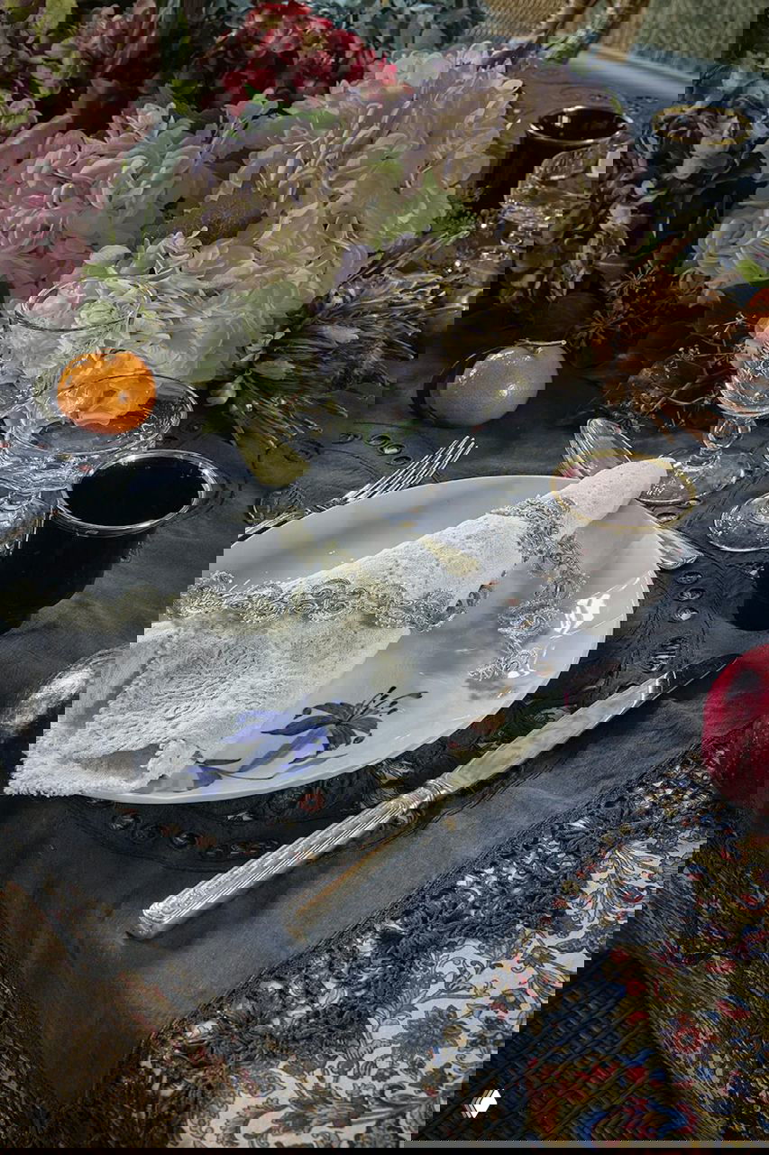 Праздничная сервировка стола: фарфоровая тарелка с кружевной салфеткой, серебряные приборы, стеклянные бокалы и пышный букет гортензий на Рождество в поместье на Фюне.