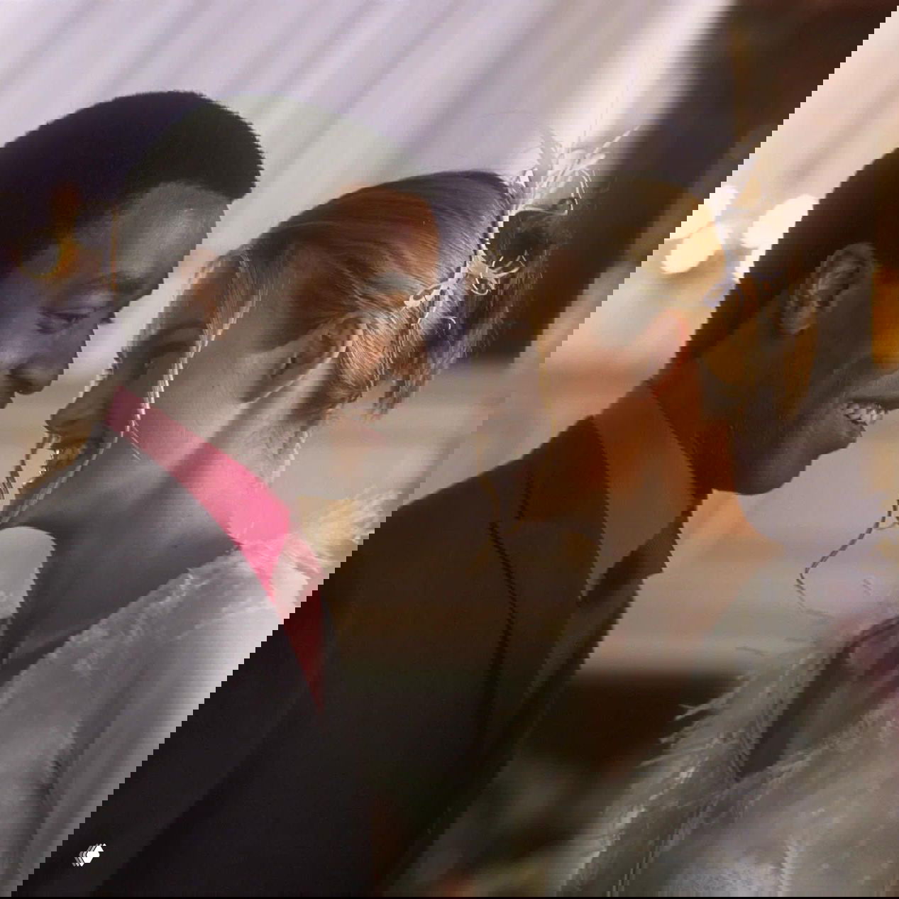 Романтический кадр: улыбающаяся пара в вечерних нарядах встречается в светлой сцене — тёплый момент из праздничной романтической комедии.