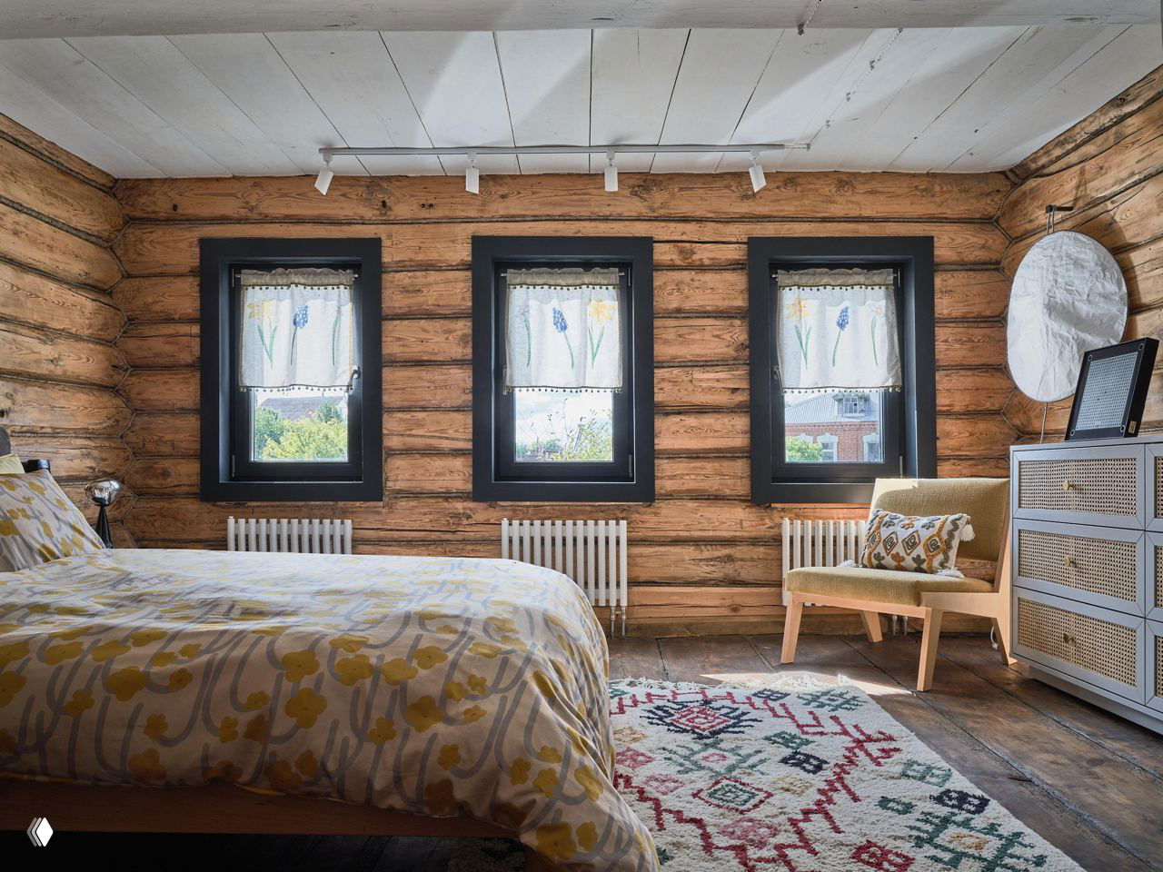 Спальня в гостевом доме: внутренние стены из натурального дерева, текстильные занавески и деревянный пол создают уютную атмосферу.