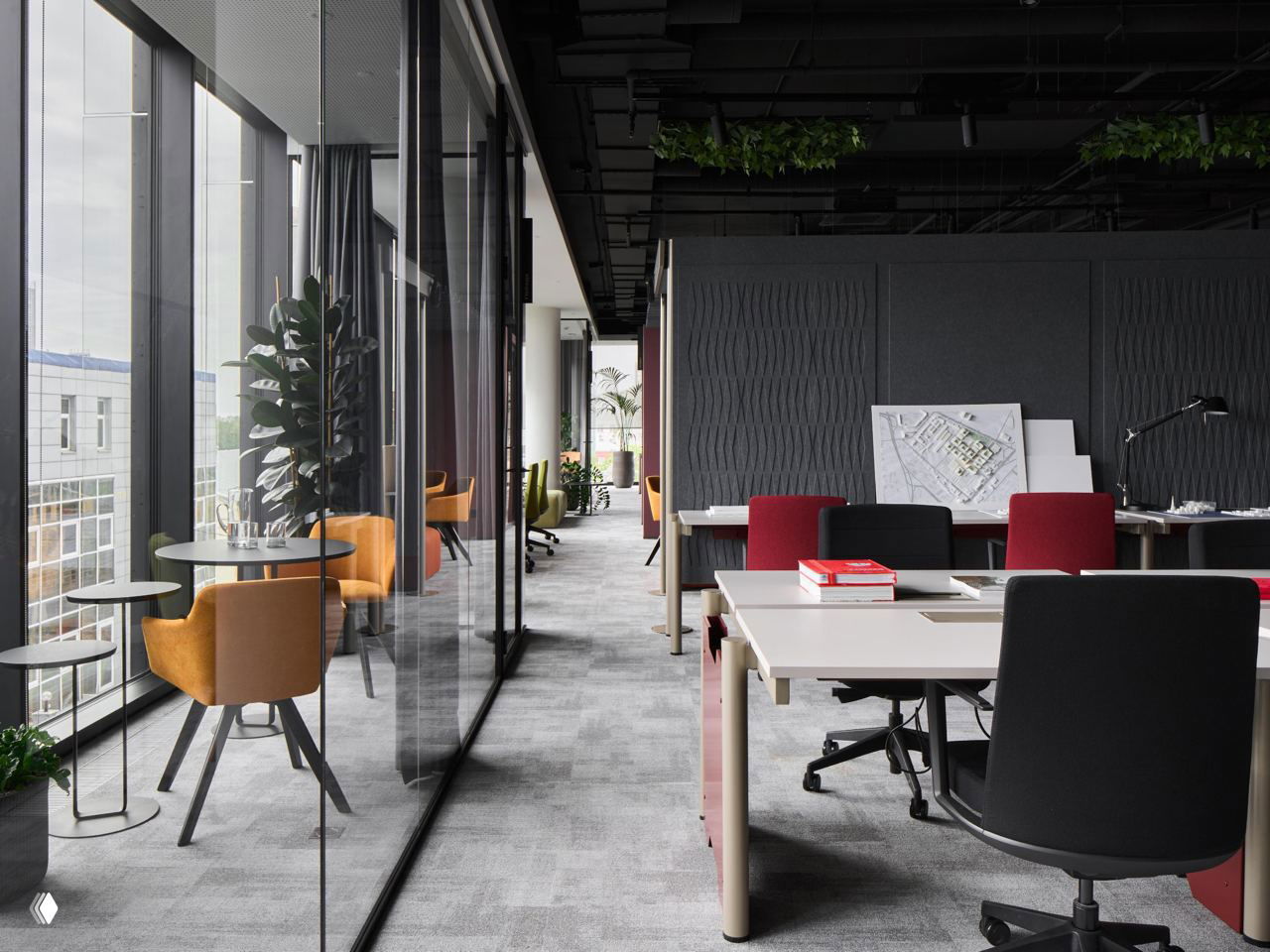 Ряд рабочих мест у стеклянной перегородки, вид коридора вдоль фасада и небольшие столики у окна с оранжевыми креслами для одиночной работы.