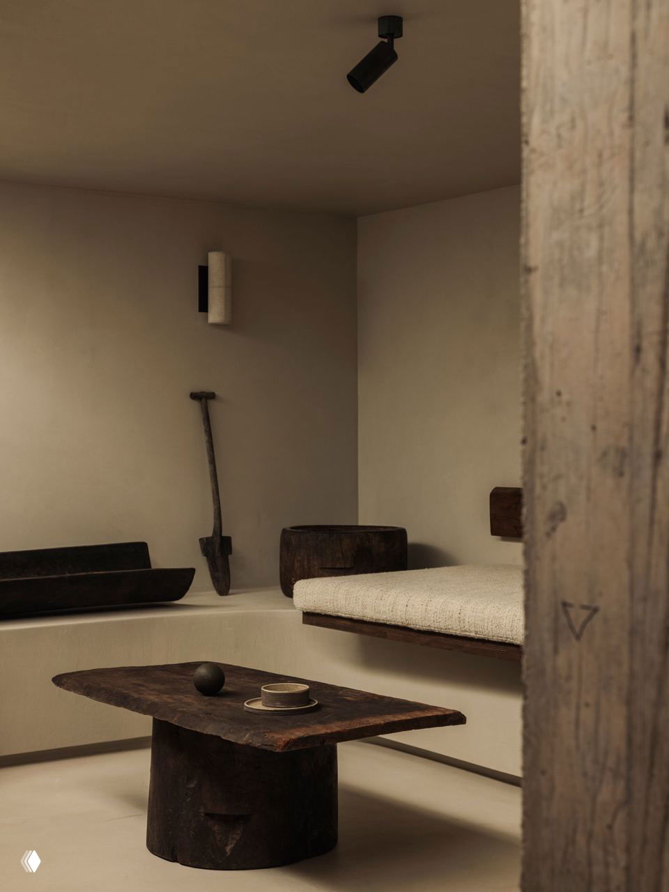 Детали интерьера шале: рустикальная мебель, скульптурные предметы и грубая текстура дерева на фоне гладкого вощеного бетонного пола и мягкого освещения.