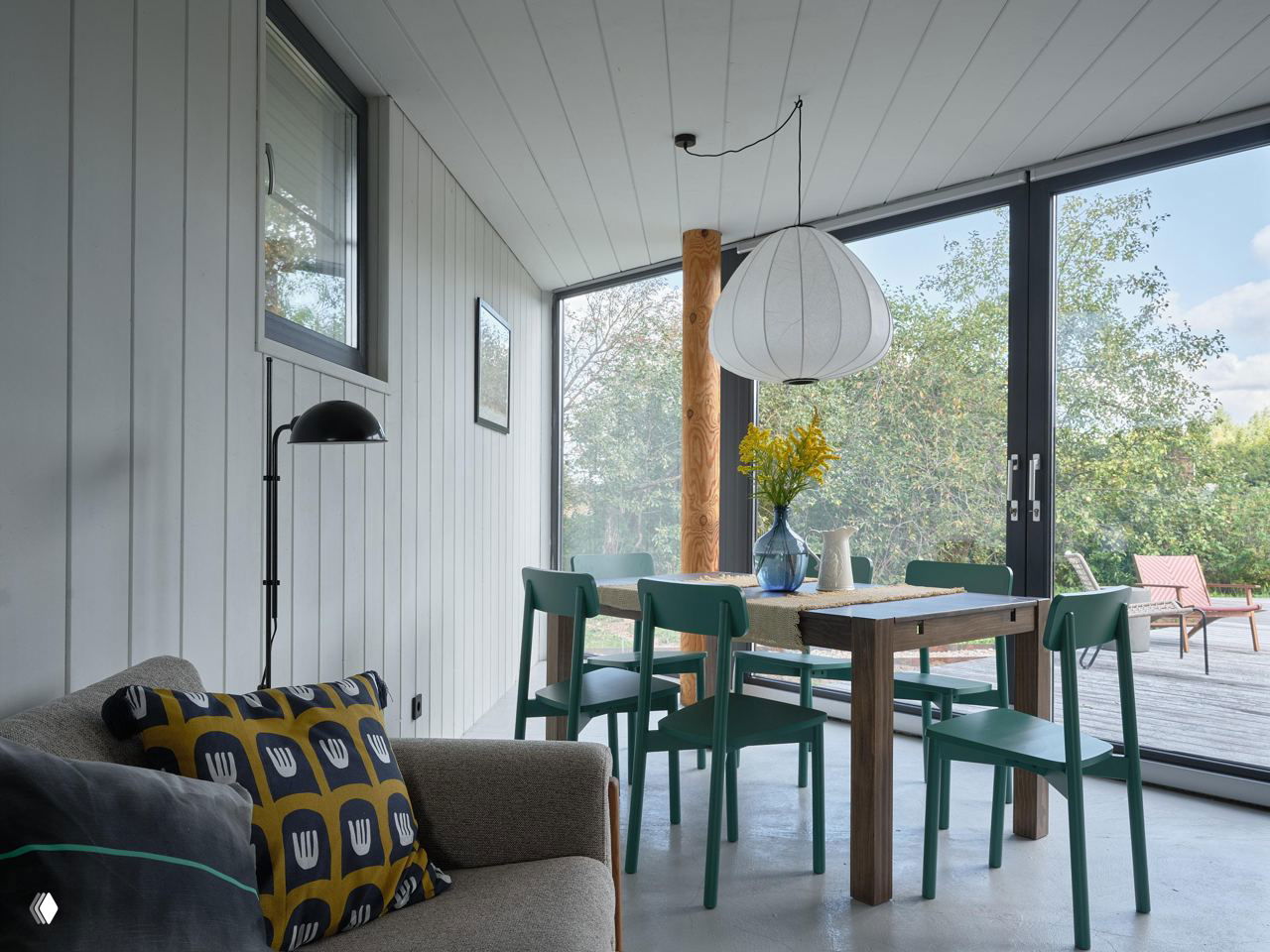 Столовая и зона отдыха с панорамными окнами: светлый интерьер, деревянная мебель и виды на сад и участок вокруг дома.