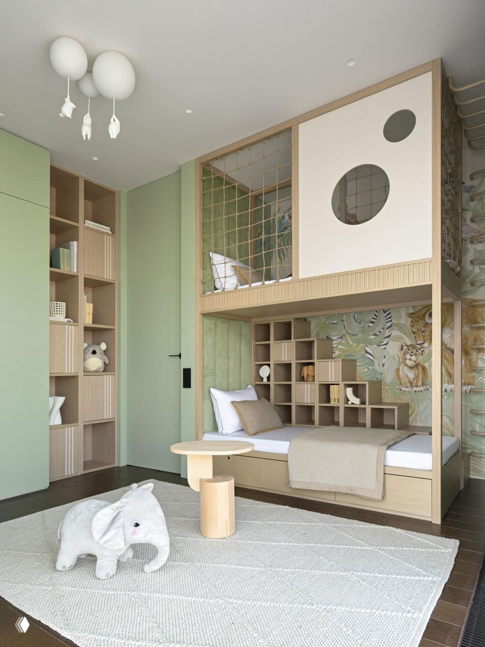 Детская в мягких нейтральных тонах и зелёных акцентах: двухъярусная зона для сна, деревянные полки, плюшевый слонёнок и текстильные элементы на светлом полу.