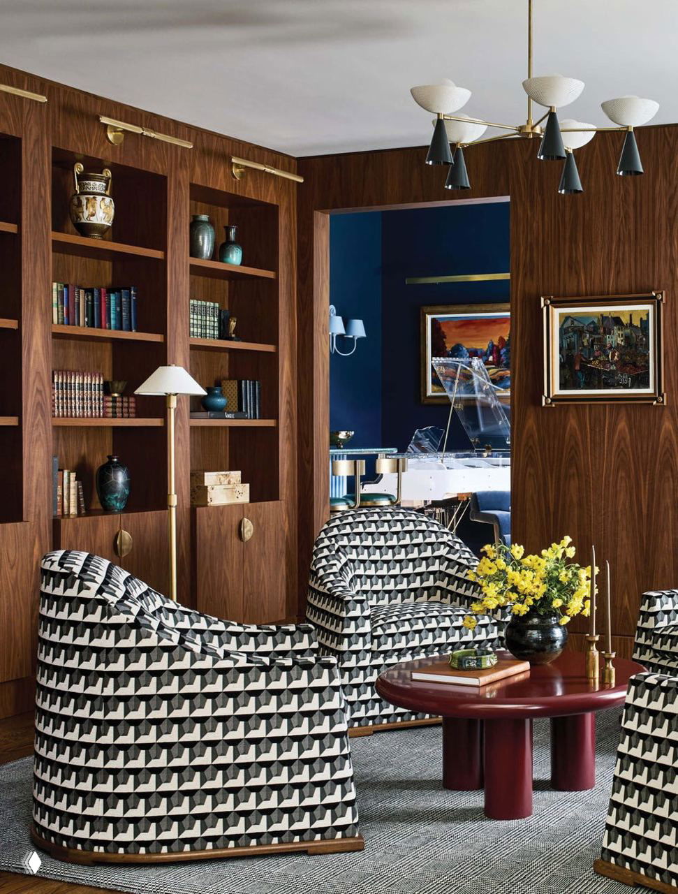 Гостиная с деревянными панелями, геометрическими мягкими креслами в черно‑белом рисунке, низким столиком и видом в музыкальную комнату с роялем, подчёркивающая смешение текстур.