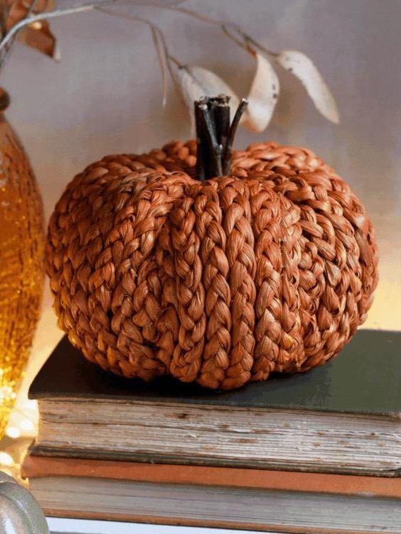 Плетёная декоративная тыква на стопке книг — текстурный изысканный акцент для осеннего и хэллоуин‑декора в интерьере.