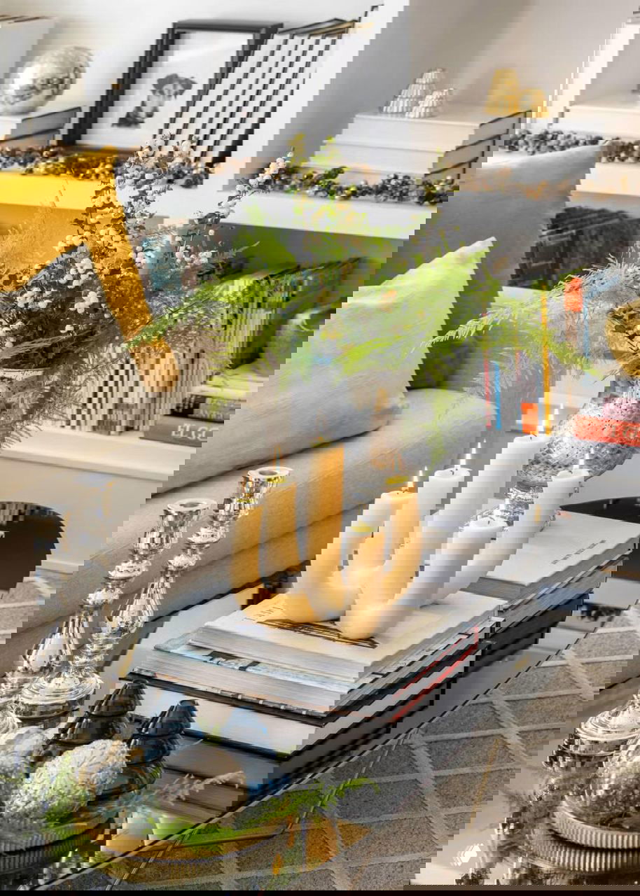 Кофейный столик с книгами, декоративными свечами и вазой с зелеными цветами — комбинация текстиля, свечей и цветочных композиций в тон интерьера.