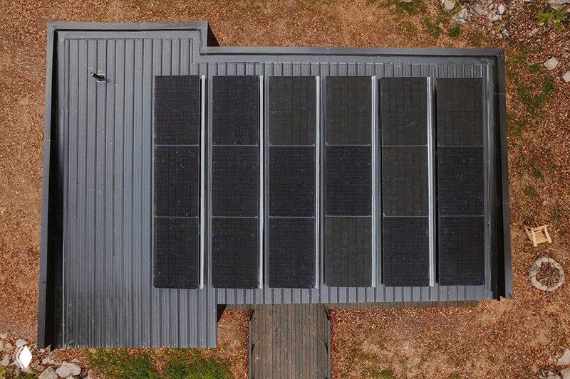 Крупный план плоской кровли с расположением панелей: видны отдельные монокристаллические модули и кровельная поверхность, часть фото искажена артефактами компрессии.