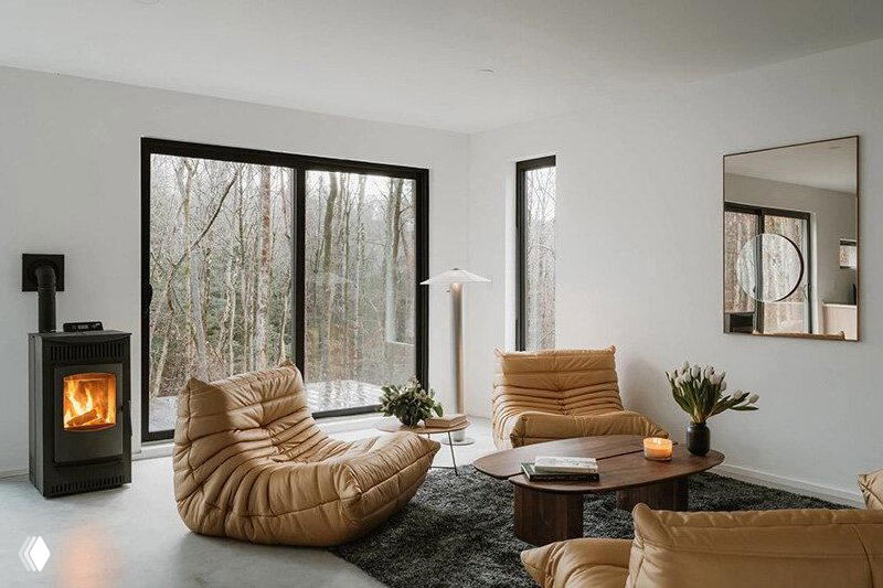 Интерьер: гостевая зона с низкими мягкими диванами и минималистичной отделкой в нейтральных тонах, большие окна обеспечивают естественный свет; изображение частично искажено пикселизацией.