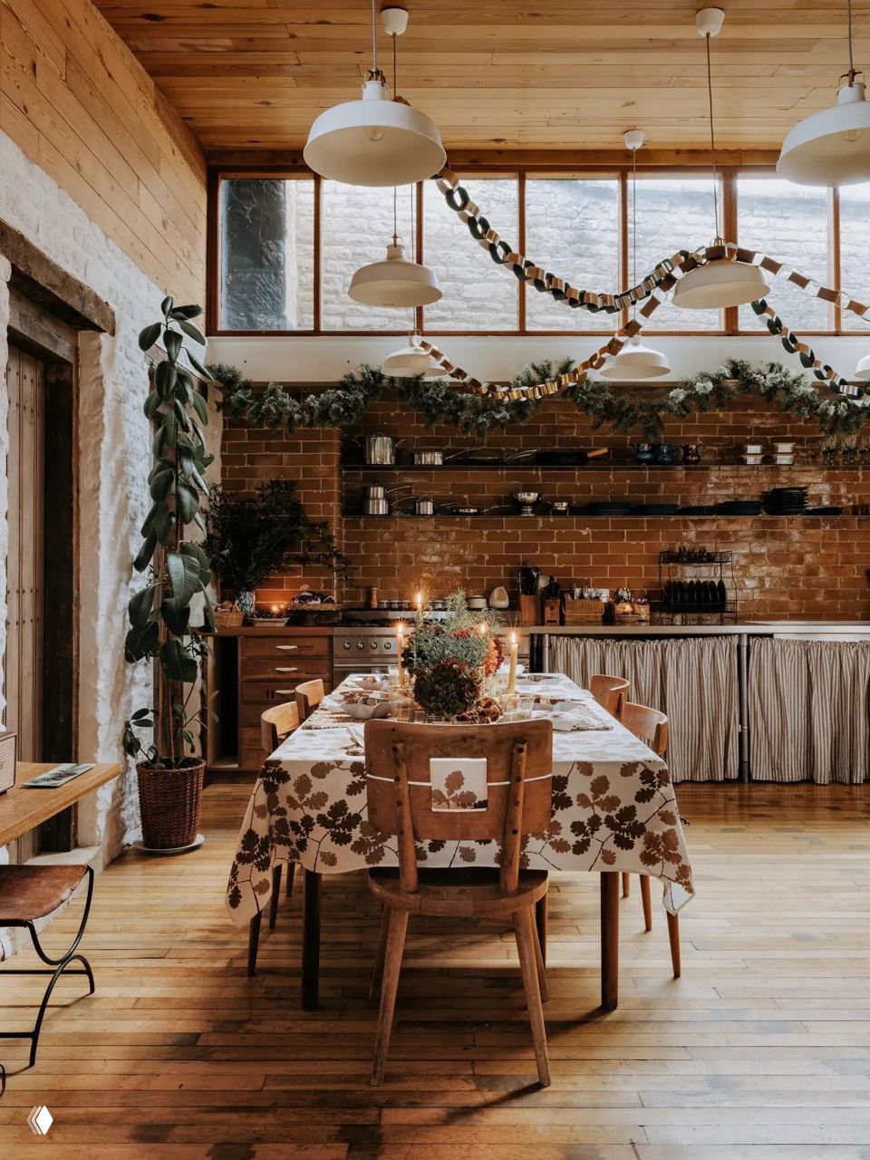 Деревянная столовая в уютной кухне с рождественской сервировкой, гирляндами на балках и зелёными декорациями для маленькой квартиры