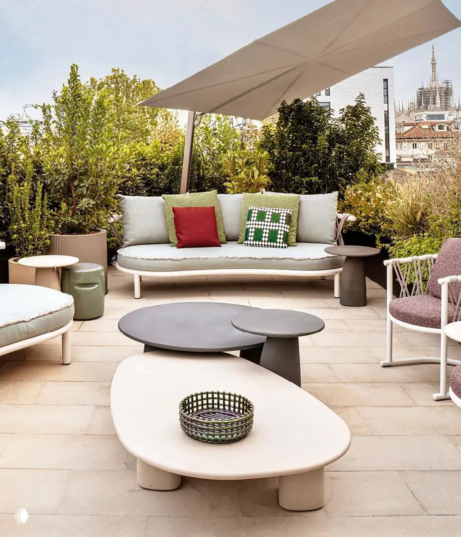 Терраса Casa Brera с лаунж-зоной: низкие столики, мягкие диваны и вид на город с растениями и зонтиком для тени.