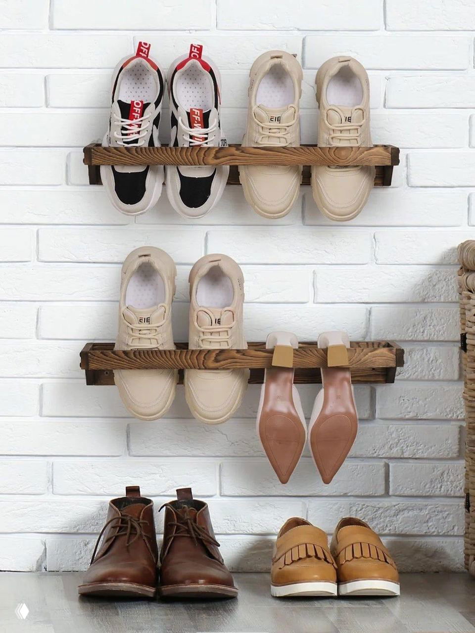 Деревянные настенные полки-держатели для пары обуви в ряд на фоне белой кирпичной стены; идея подвесного компактного хранения для стен.