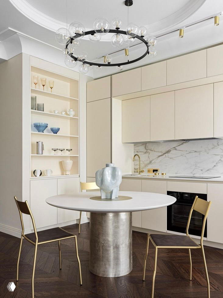 Светлая столовая и кухня: круглый стол, металлическая колонна и встроенные шкафы с полками — пример аккуратного, незаметного хранения в интерьере