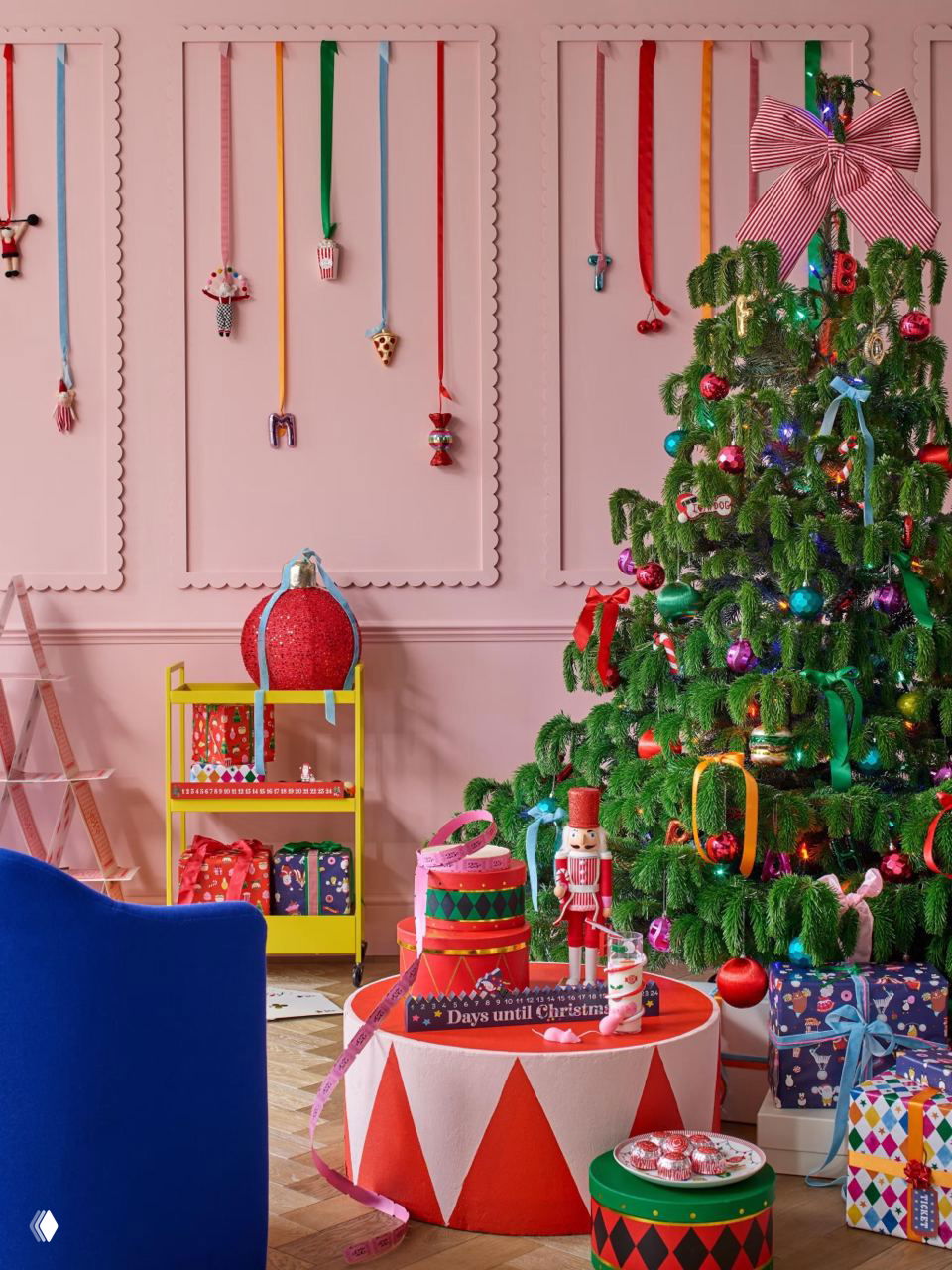 Яркая праздничная комната с розовой стеной, игрушечной ёлкой и подарками — версия новогоднего декора для маленькой гостиной