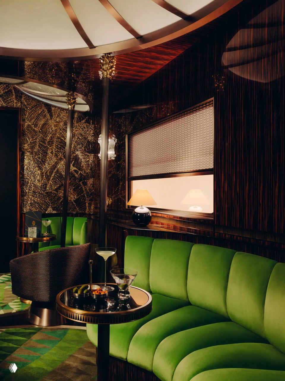 Лаунж‑зона с зелёным диваном и круглыми столиками: насыщенные материалы, бархатная обивка и орнаментальные панели в стиле ар‑деко.