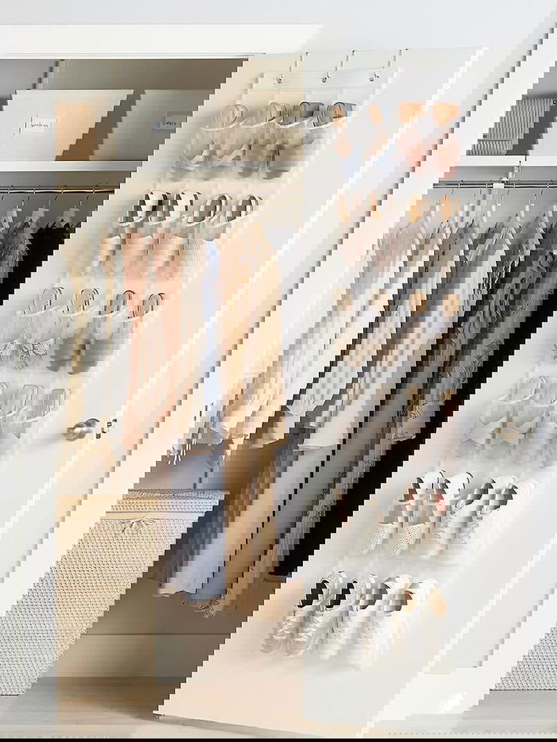 Органайзер для обуви на внутренней стороне двери: прозрачные карманы с парами кроссовок и балеток на белой двери в гардеробной.