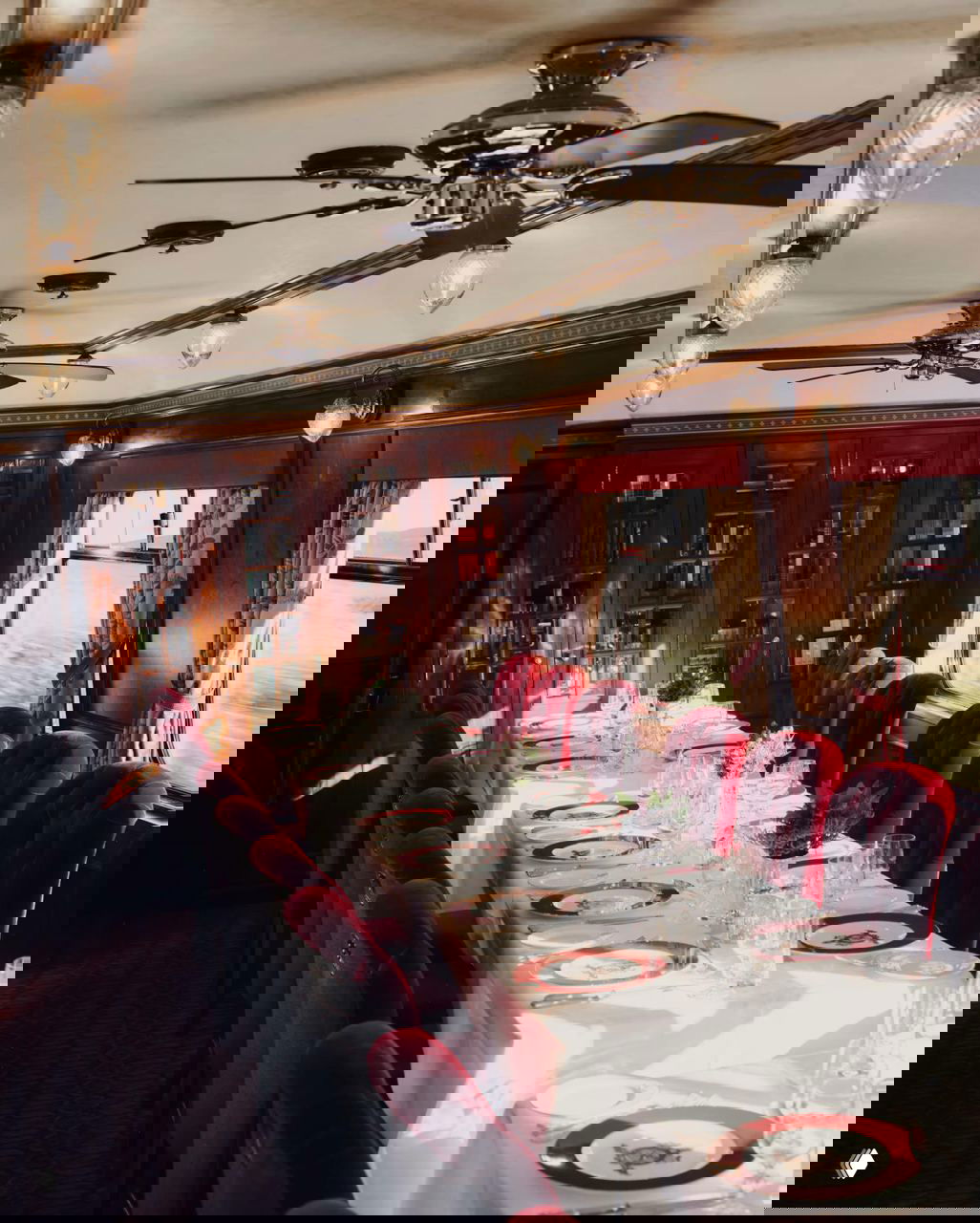 Обеденный вагон Royal Scotsman: длинный сервированный стол, белые скатерти и красные бархатные кресла, элегантная столовая атмосфера на колёсах