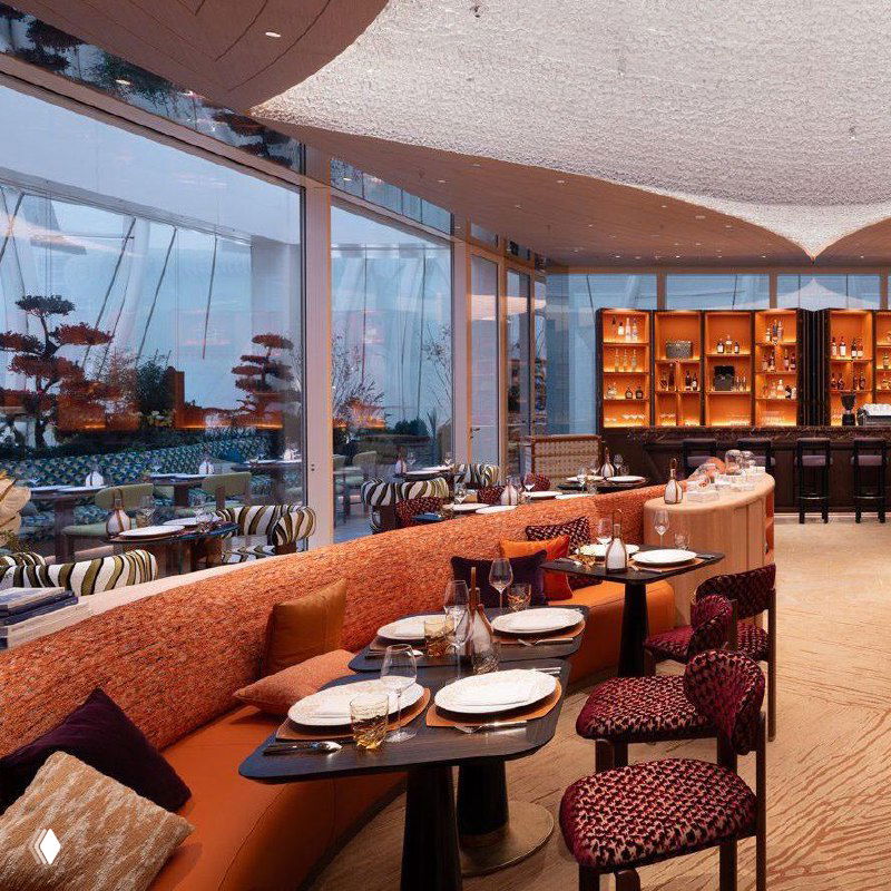 Ресторанная зона и зал кафе внутри флагмана Louis Vuitton: обеденные столы, панорамные окна и вид на фасадный стеклянный «хамелеон».