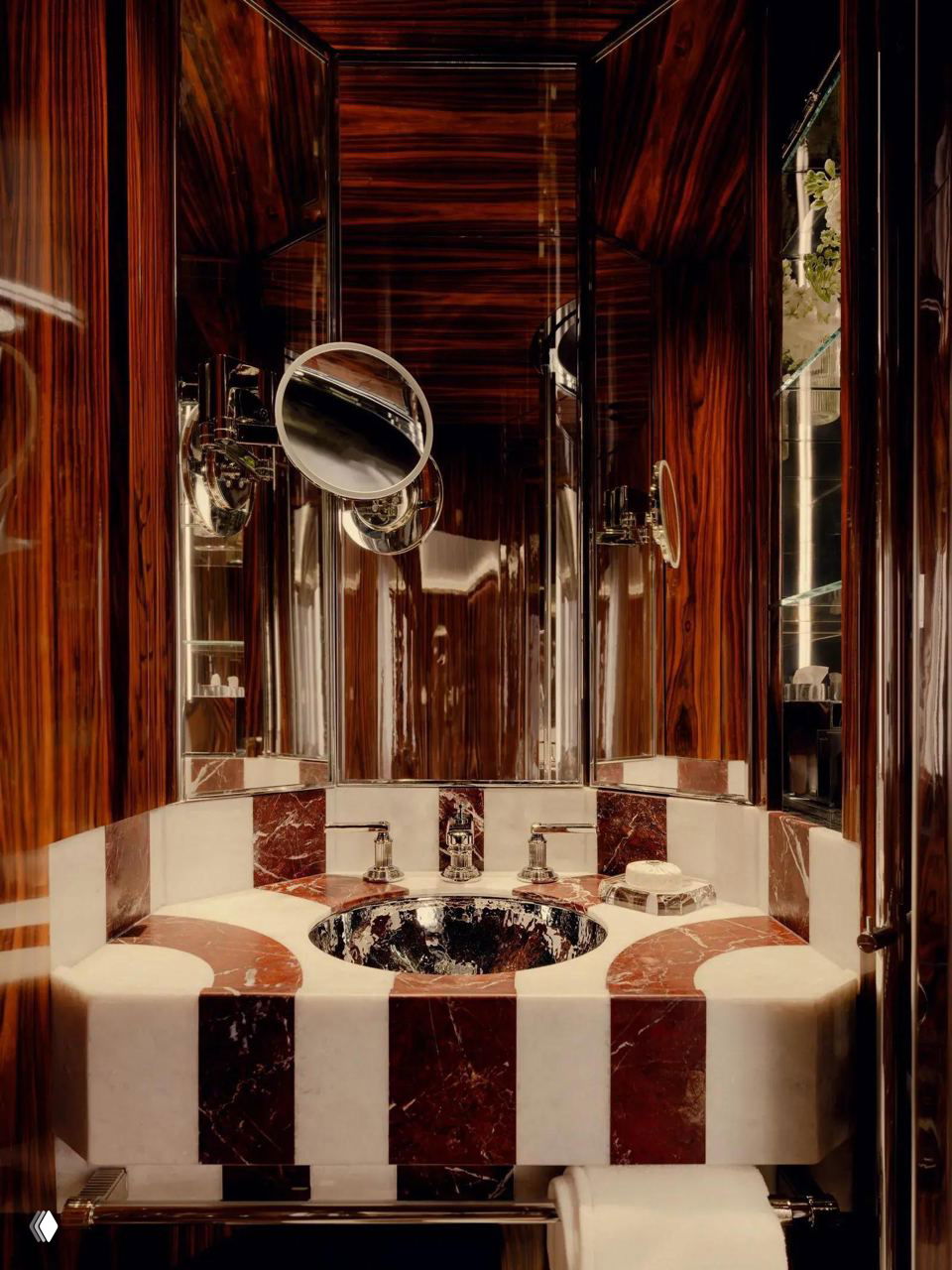 Ванная комната вагона с мраморной раковиной в полосах, зеркальными поверхностями и полированной деревянной отделкой — акцент на ручной работе и роскоши.