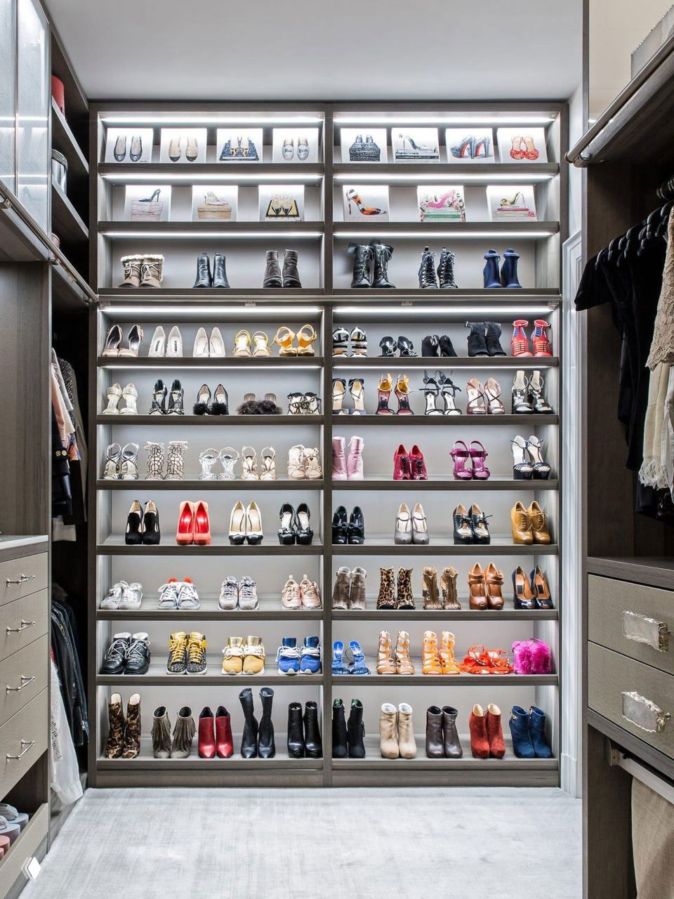 Высокий встроенный стеллаж с подсветкой, на полках аккуратно размещены туфли, ботильоны и сапоги — эффект бутика в гардеробе.