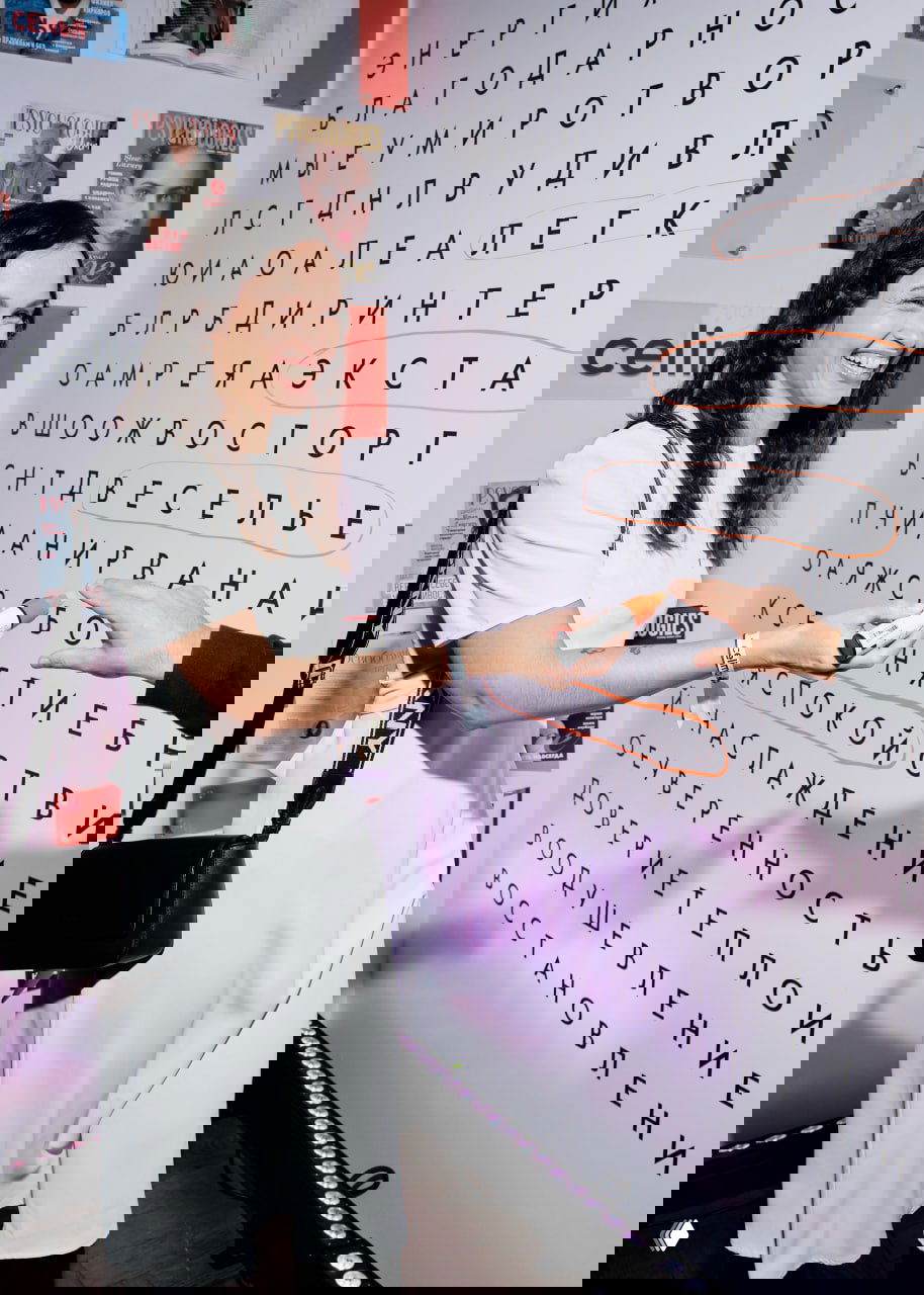 Улыбающаяся гостья отмечает слово на настенной игре-таблице: яркое оформление, улыбающиеся лица и праздничная атмосфера вечера.