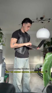 Человек стоит с ноутбуком в руках и читает — вероятно, репетиция или подготовка ролика, отражение темы обучения русскому языку.