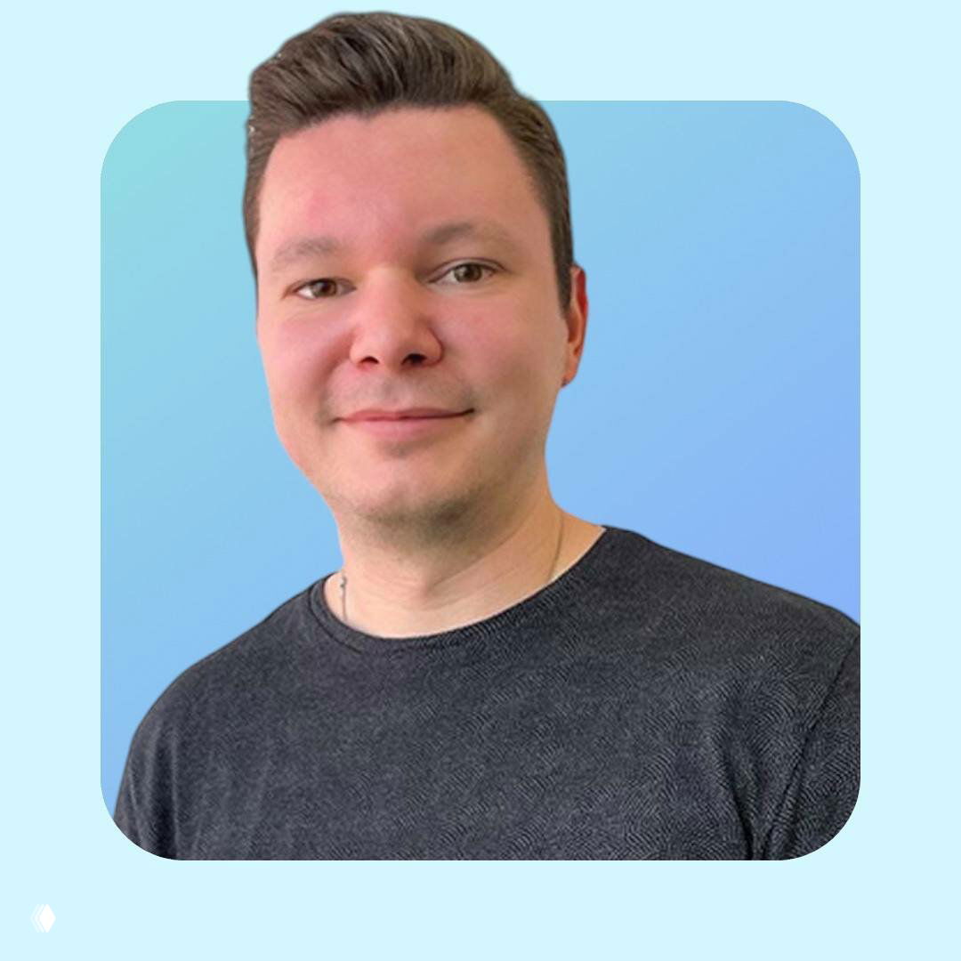 Портрет улыбающегося мужчины в тёмной футболке на светло-голубом фоне, крупный план лица и плеч, изображение используется как аватар автора канала о психологии.