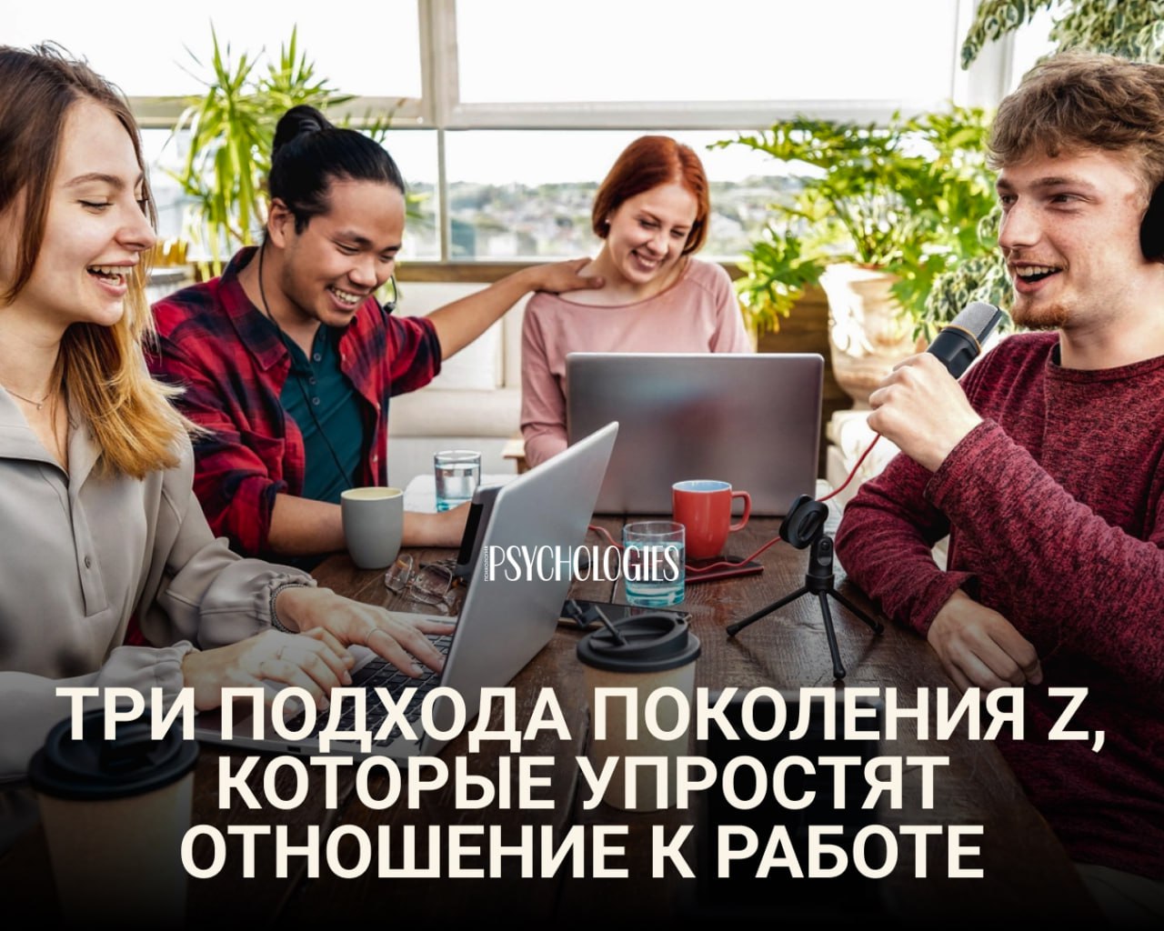 Группа молодых людей поколения Z за столом с ноутбуками и микрофоном, обсуждают работу и улыбаются в светлом креативном пространстве